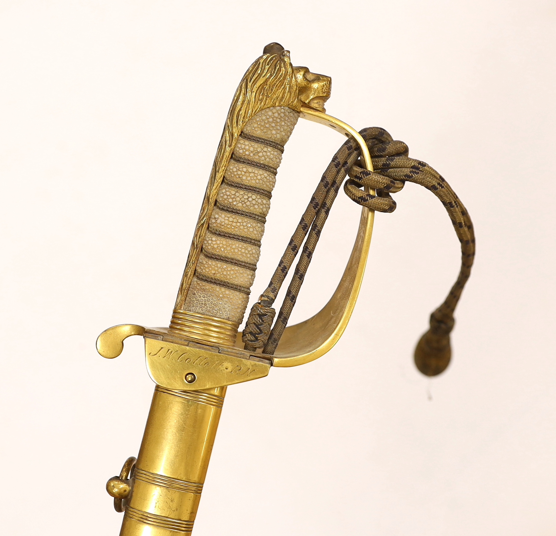 A World War I naval sword with folding guard engraved J.W. Collett R.N., regulation gilt hilt and scabbard mounts, the blade has been refinished and furniture regilded, with bullion dress knot, blade 78.5cm